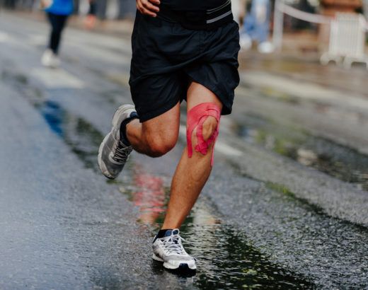 Kinesiotaping w sporcie - biegacz z różowymi plastrami na kolanie