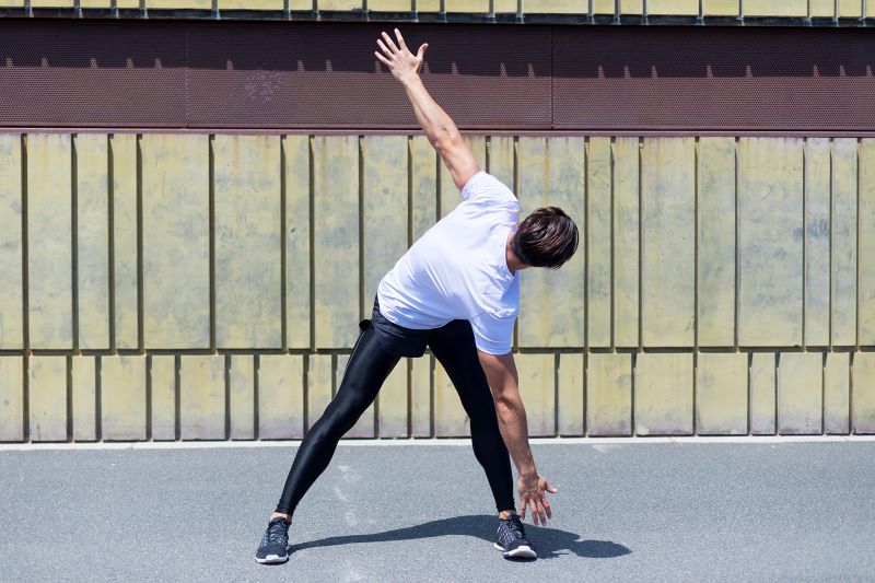 mężczyzna rozgrzewa się przed joggingiem - skrętoskłony