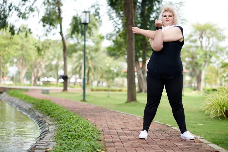 kobieta plus size robi rozgrzewkę przed joggingiem